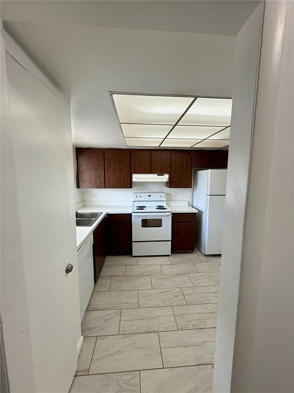 A kitchen with wood cabinets, white appliances, and light-colored tile flooring — 7047 BALBOA DRIVE UNIT 7047, ORLANDO, FL