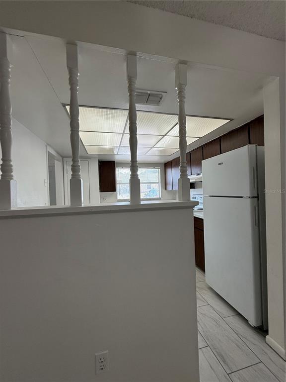 A kitchen with white appliances, dark wood cabinets, and a partial wall with decorative spindles — 7047 BALBOA DRIVE UNIT 7047, ORLANDO, FL