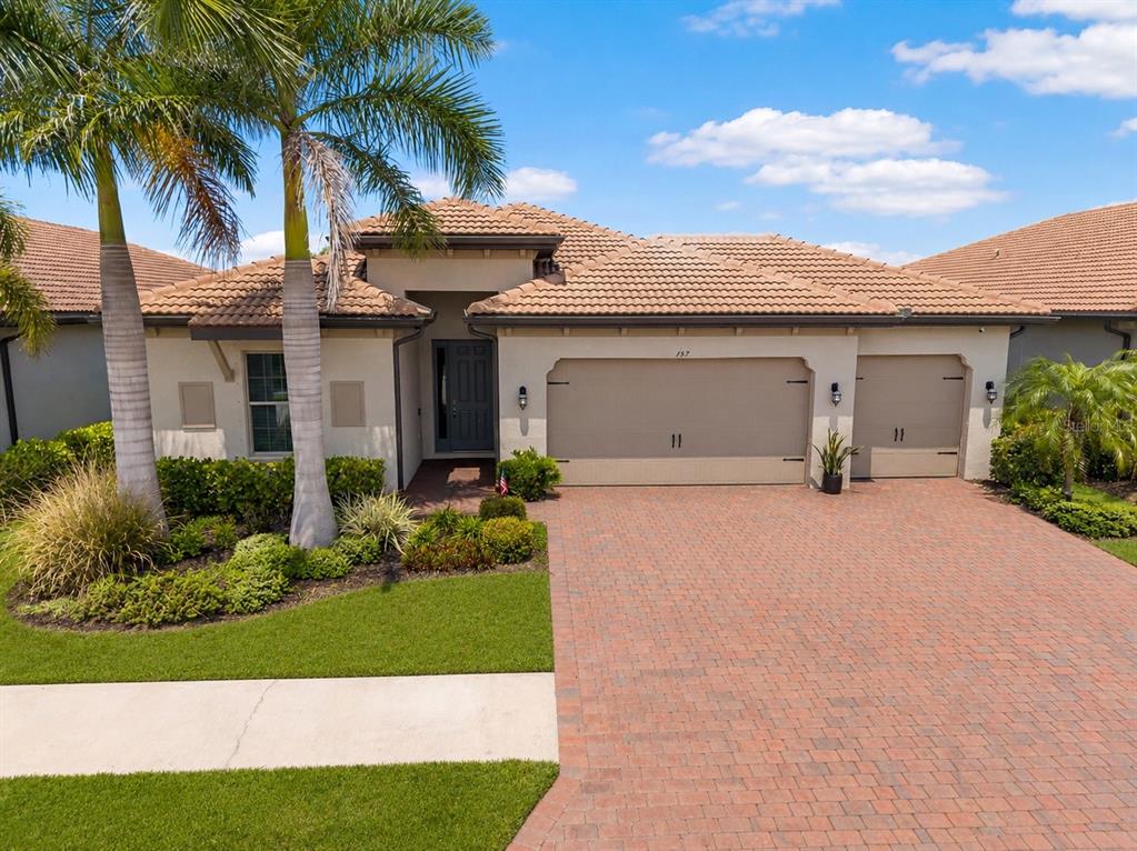 A single-story house with a tiled roof, a brick driveway, and a three-car garage — 157 VERAZA COURT, NOKOMIS, FL