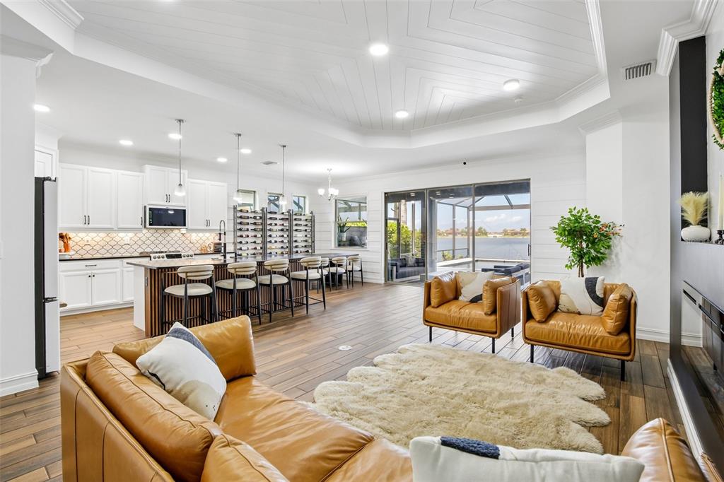 An open-concept living room and kitchen with white cabinetry, leather furniture, and waterfront views — 157 VERAZA COURT, NOKOMIS, FL