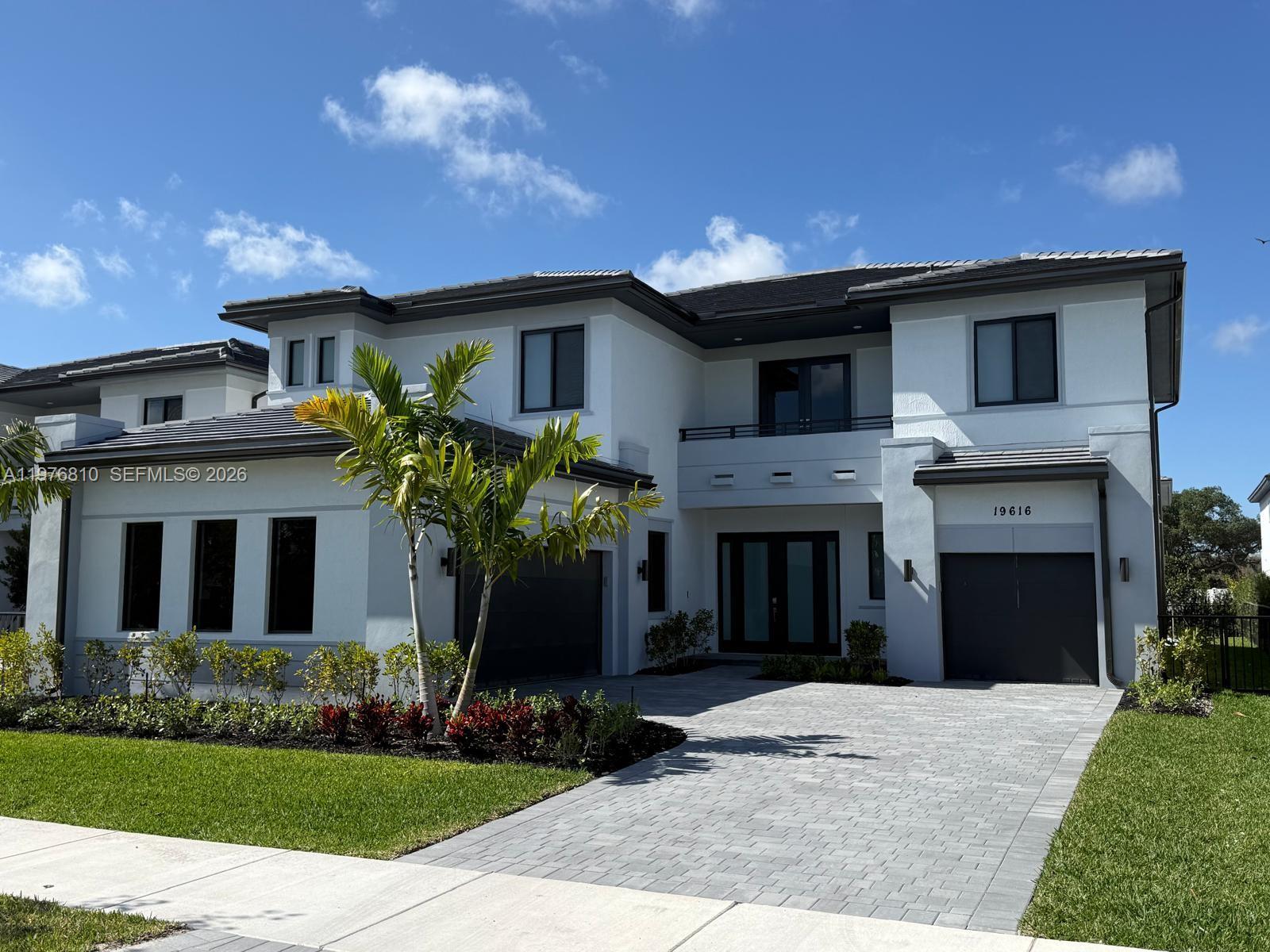 A two-story modern house features a gray tiled roof, white stucco exterior, and two garages — 19616 NE 14 CT, Miami FL 33179, MIAMI, FL