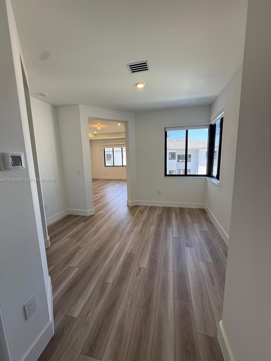This room features light wood-look flooring, white walls, and a window overlooking neighboring buildings — 19616 NE 14 CT, Miami FL 33179, MIAMI, FL