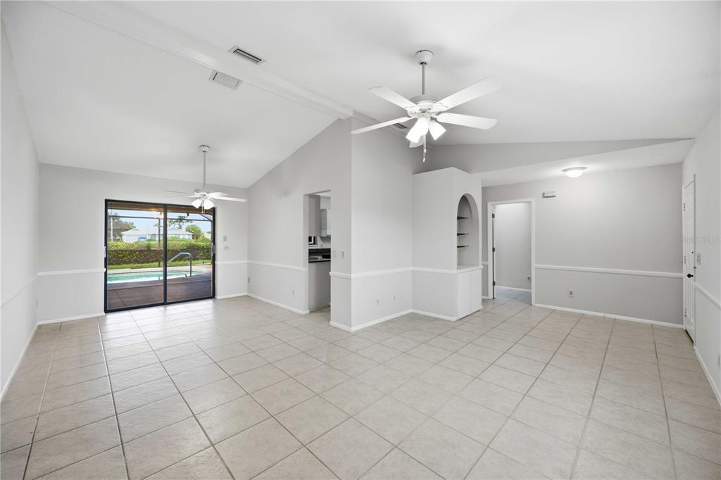 A spacious living area with tile floors, vaulted ceilings, ceiling fans, and a sliding glass door — 2221 MAURITANIA ROAD, PUNTA GORDA, FL