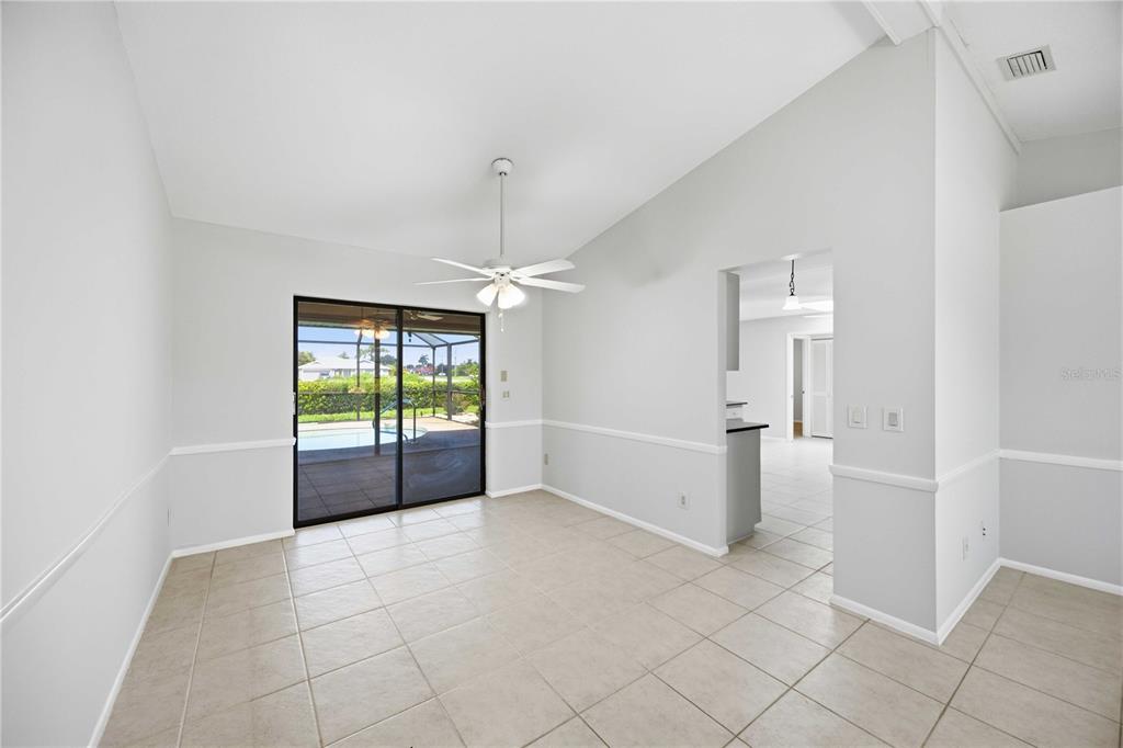A dining area with tile floors, a ceiling fan, and sliding doors leading to a pool — 2221 MAURITANIA ROAD, PUNTA GORDA, FL