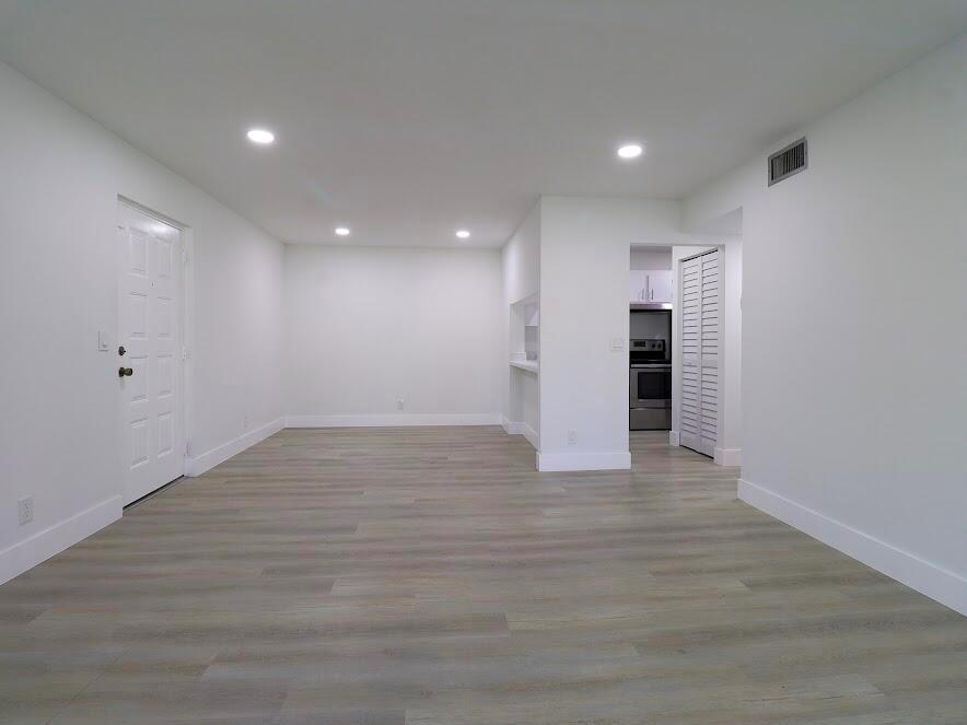 A bright, empty room features white walls, recessed lighting, and light-toned wood-look flooring — 614 Sea Pine Way # H2, FL 33415, FL