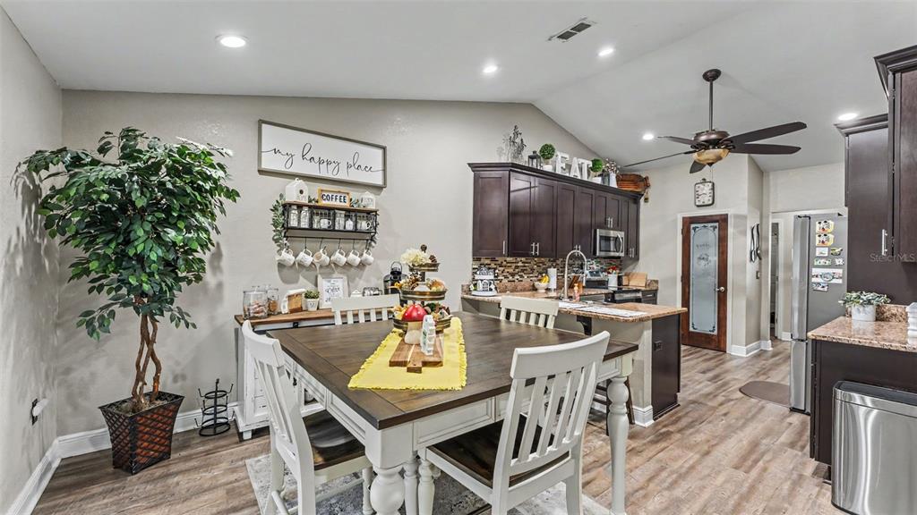 A dining area with a wooden table and white chairs sits adjacent to a dark-cabinet kitchen — 1411 ASHBURY COURT, LAKELAND, FL