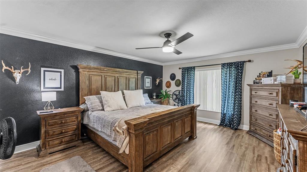 A bedroom features a wooden bed frame, a black accent wall, and wood-look flooring — 1411 ASHBURY COURT, LAKELAND, FL