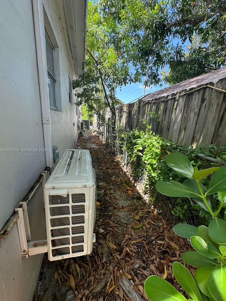 A narrow side yard features an exterior air conditioning unit next to a wooden fence — 685 SW 7th Ter, Dania Beach FL 33004, DANIA BEACH, FL