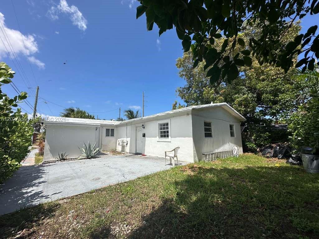 A white, single-story house with a concrete driveway and a grassy yard under a blue sky — 685 SW 7th Ter, Dania Beach FL 33004, DANIA BEACH, FL