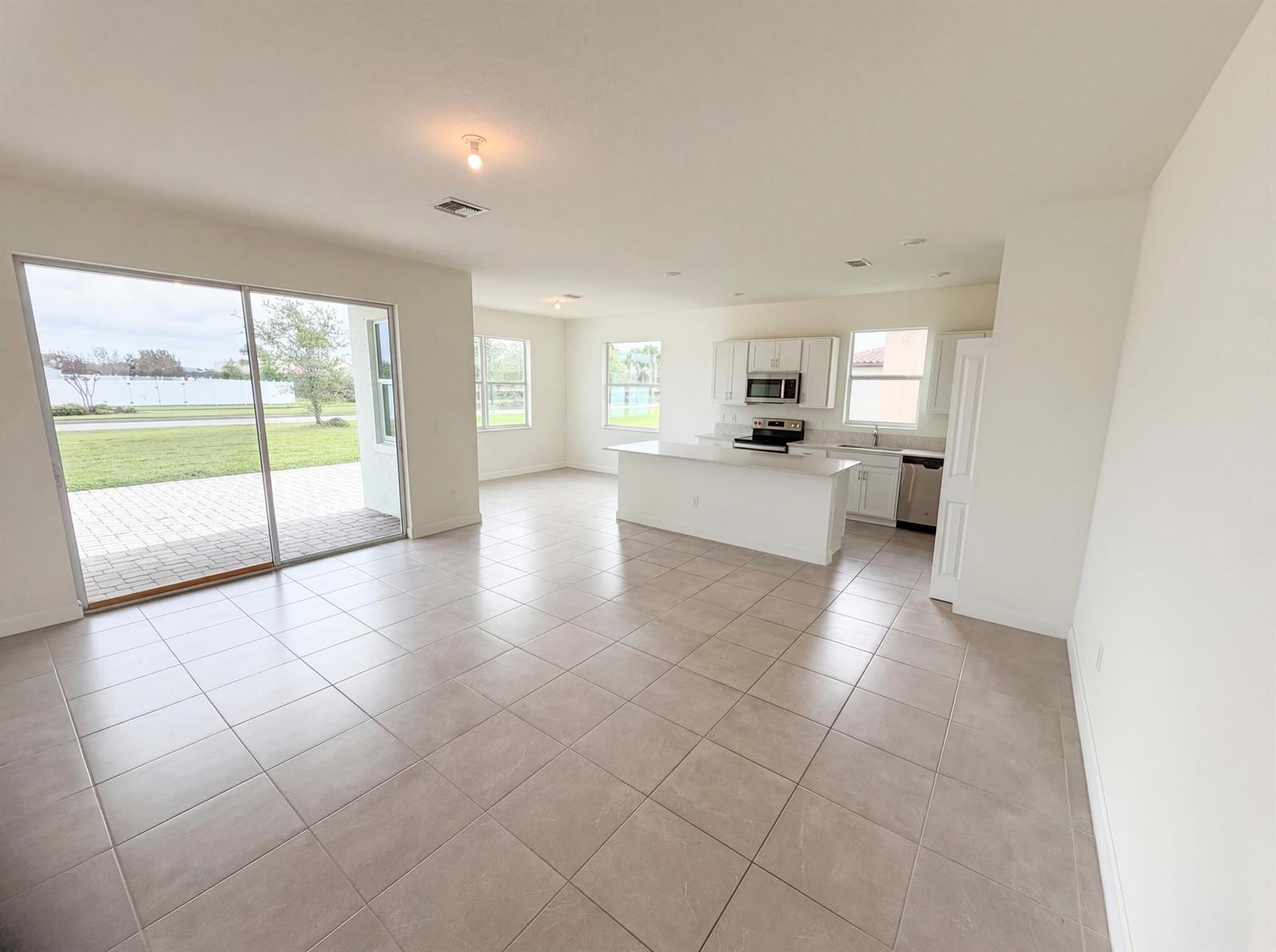 An open-concept kitchen and living area features white cabinetry, a center island, and tile flooring — 12473 NW Lynch Lane, FL 34987, FL