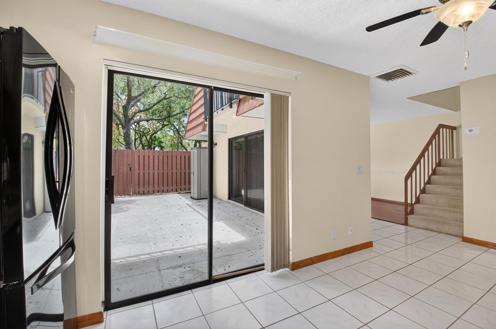 A room with white tile floors, a sliding glass door to a patio, and stairs — 1565 Augusta Circle # 103, Delray Beach FL 33445, DELRAY BEACH, FL