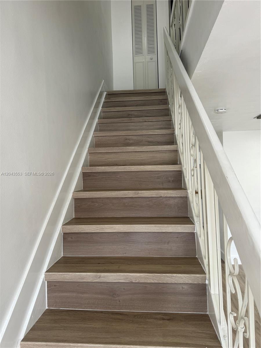 A staircase with wood-look treads and white railings leads to a landing with louvered doors — 6250 SW 130th Ave # 702, Miami FL 33183, MIAMI, FL