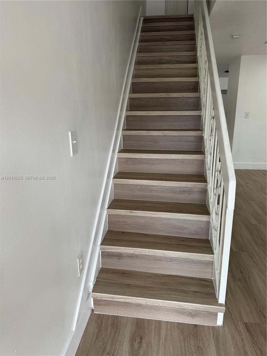 A straight staircase with wood-look treads and white risers features a decorative metal railing — 6250 SW 130th Ave # 702, Miami FL 33183, MIAMI, FL