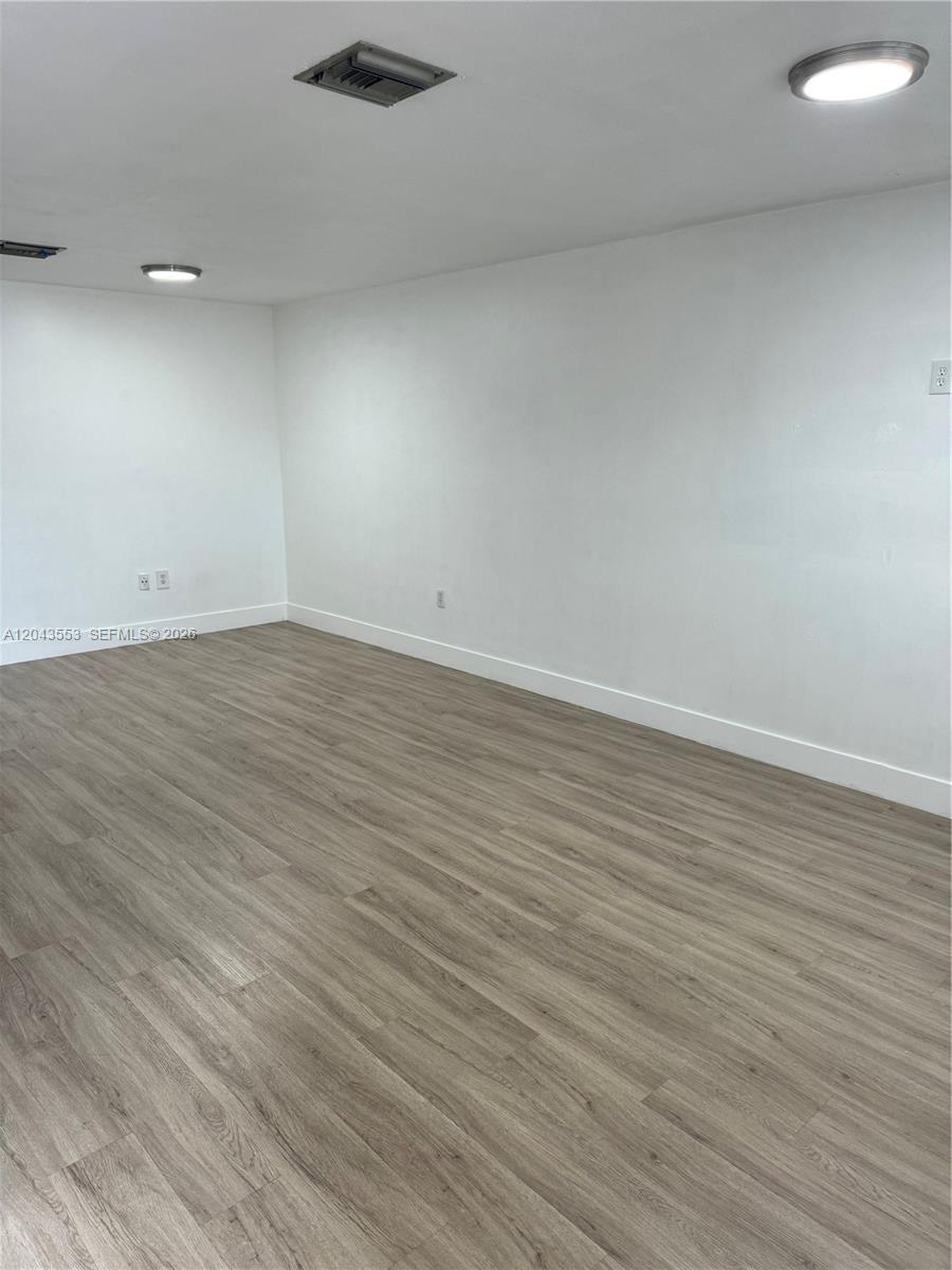 An empty room features white walls, light wood-look flooring, and two ceiling-mounted light fixtures — 6250 SW 130th Ave # 702, Miami FL 33183, MIAMI, FL