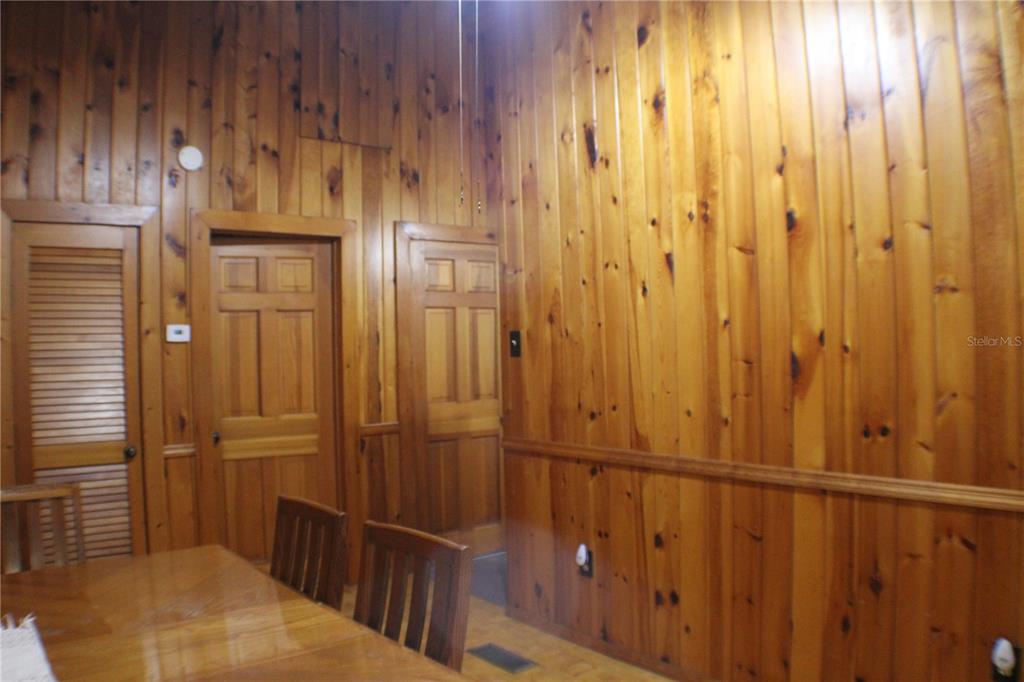 A dining room features wood-paneled walls, a wooden table, and three wooden doors — 3045 YORKSHIRE DRIVE, DELTONA, FL