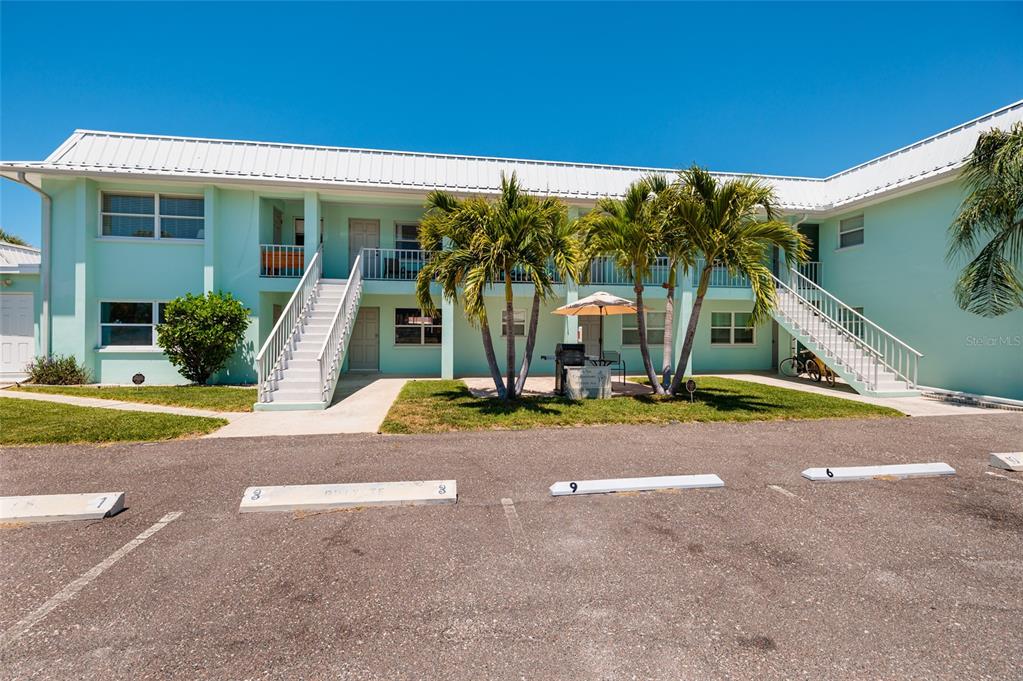 A two-story light green apartment building with exterior staircases and palm trees in front — 10 164TH AVENUE UNIT 1, REDINGTON BEACH, FL