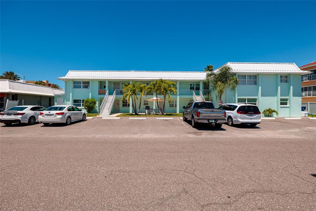 A two-story, light green apartment building with a white metal roof and parking lot — 10 164TH AVENUE UNIT 1, REDINGTON BEACH, FL