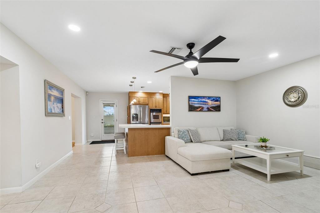 A living room with tile floors, a sectional sofa, and an open kitchen with wood cabinets — 12946 88TH AVENUE, SEMINOLE, FL