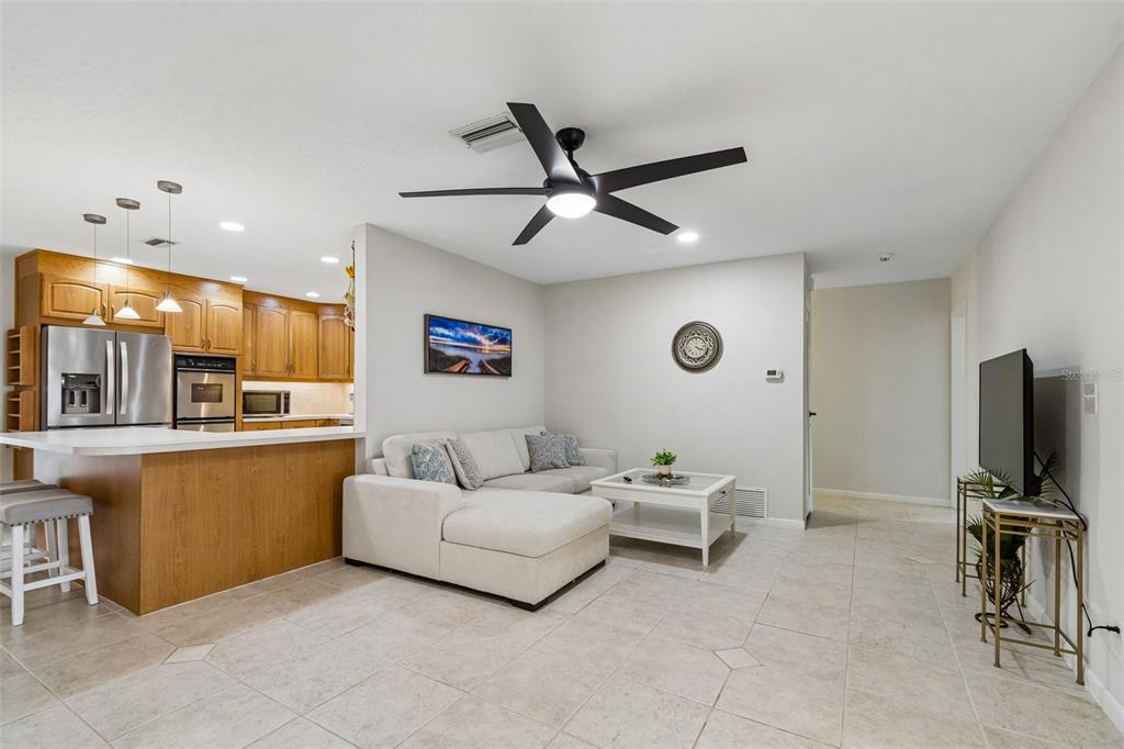 An open-concept living room features a white sectional sofa, a coffee table, and a kitchen — 12946 88TH AVENUE, SEMINOLE, FL