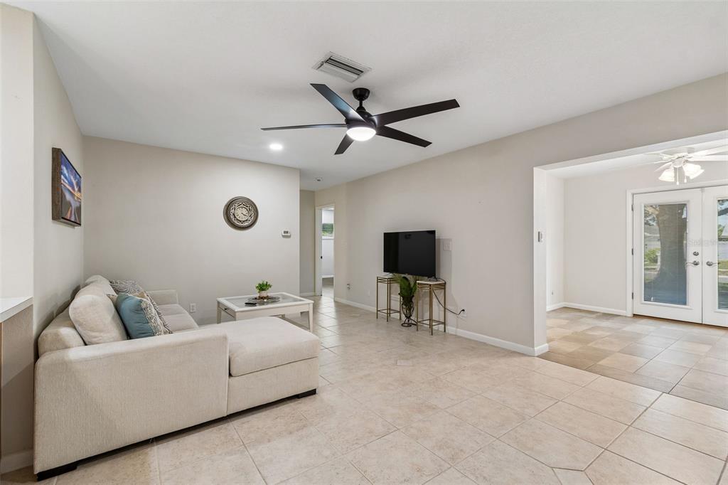 A living room features a beige sectional sofa, a television on a stand, and tile flooring — 12946 88TH AVENUE, SEMINOLE, FL