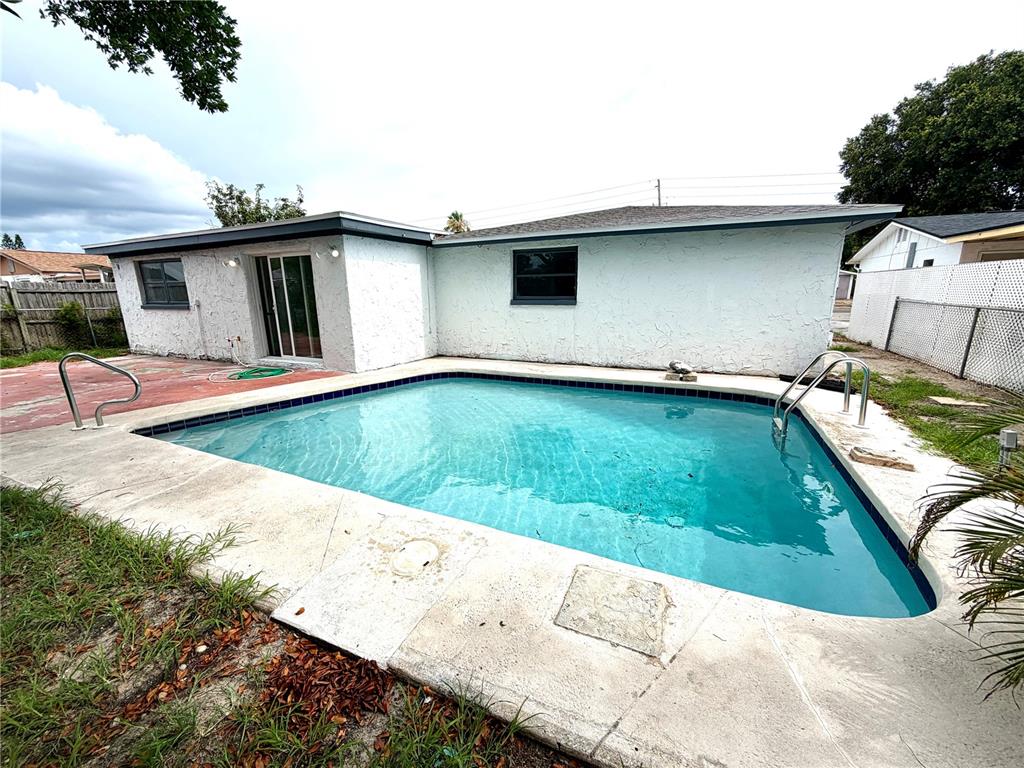 A white house exterior features a rectangular swimming pool with a concrete deck — 3331 DARLINGTON ROAD, HOLIDAY, FL