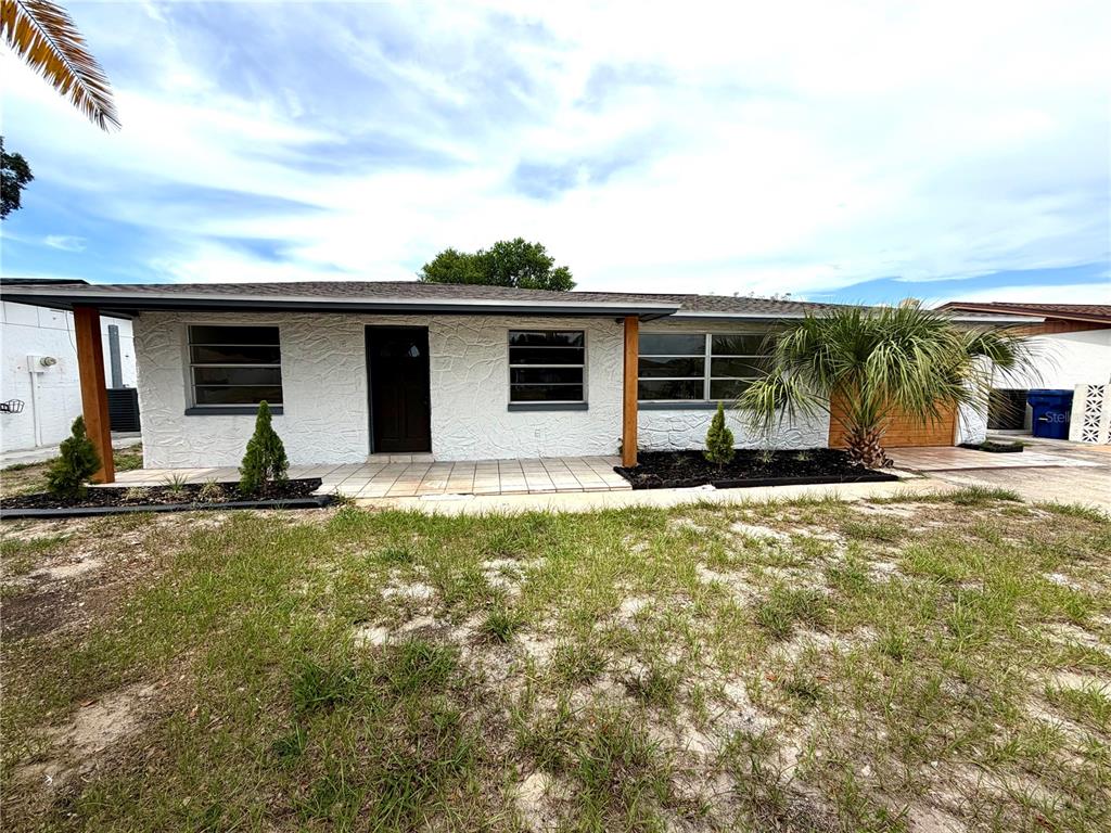 A single-story house with a white textured exterior, a covered entryway, and a front lawn — 3331 DARLINGTON ROAD, HOLIDAY, FL