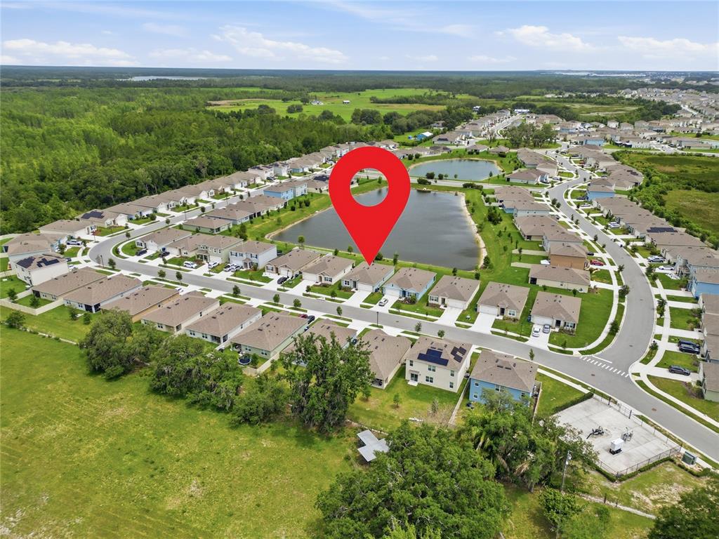 An aerial view shows a suburban neighborhood with houses surrounding a central pond — 995 BROOKLET DR, DAVENPORT, FL