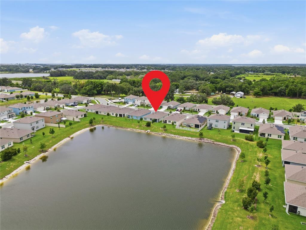 An aerial view shows a suburban neighborhood with houses surrounding a central retention pond — 995 BROOKLET DR, DAVENPORT, FL