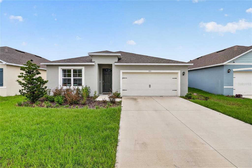 A single-story house with a gray exterior, a two-car garage, and a front lawn — 995 BROOKLET DR, DAVENPORT, FL