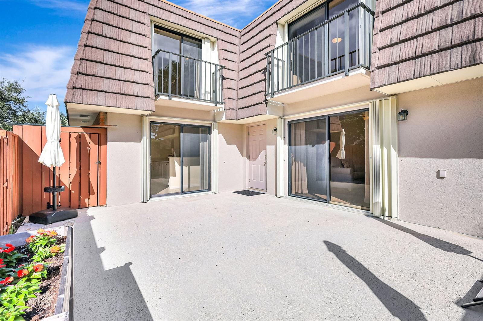 A concrete patio sits in front of a two-story building with balconies and sliding doors — 2332 23rd Court # 57d, Jupiter FL 33477, JUPITER, FL