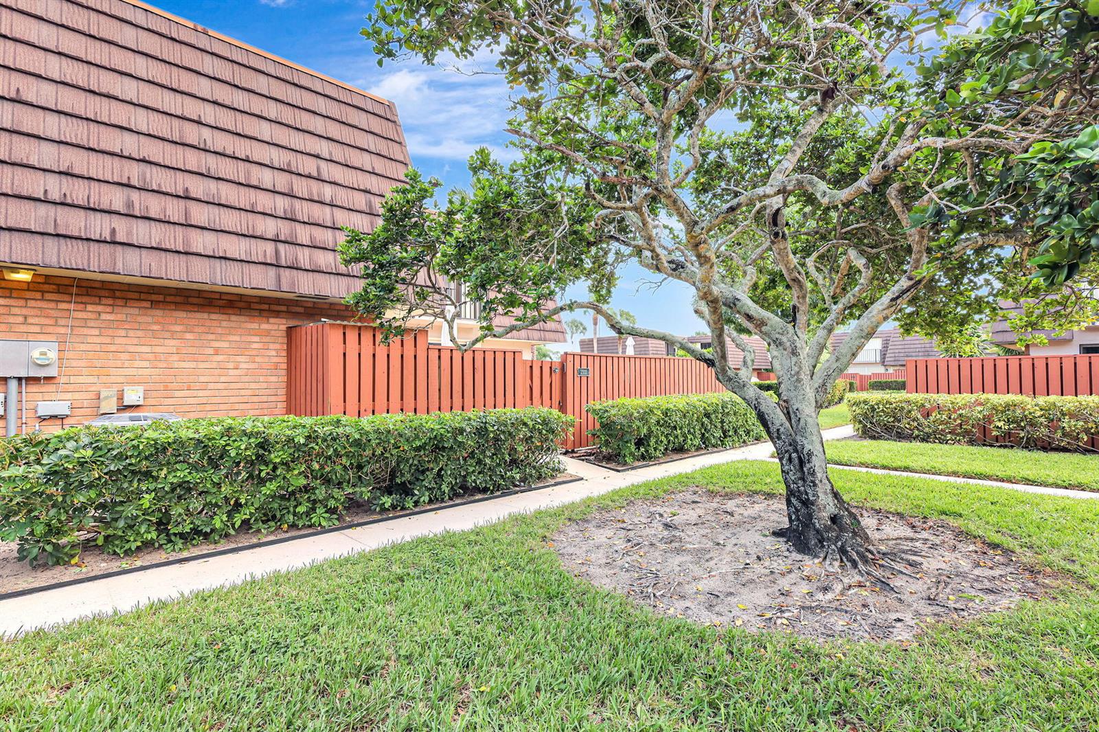 A brick building with a brown mansard roof sits behind a hedge and a tree — 2332 23rd Court # 57d, Jupiter FL 33477, JUPITER, FL