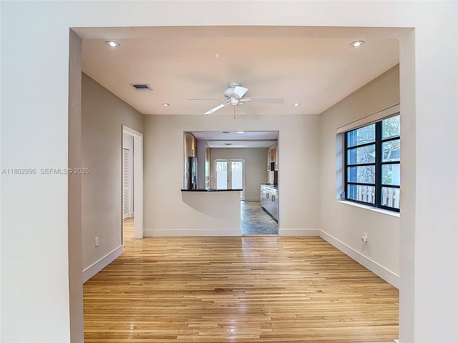 A dining room with hardwood floors looks through a pass-through window into a kitchen — 2810 Crystal Ct, Miami FL 33133, MIAMI, FL