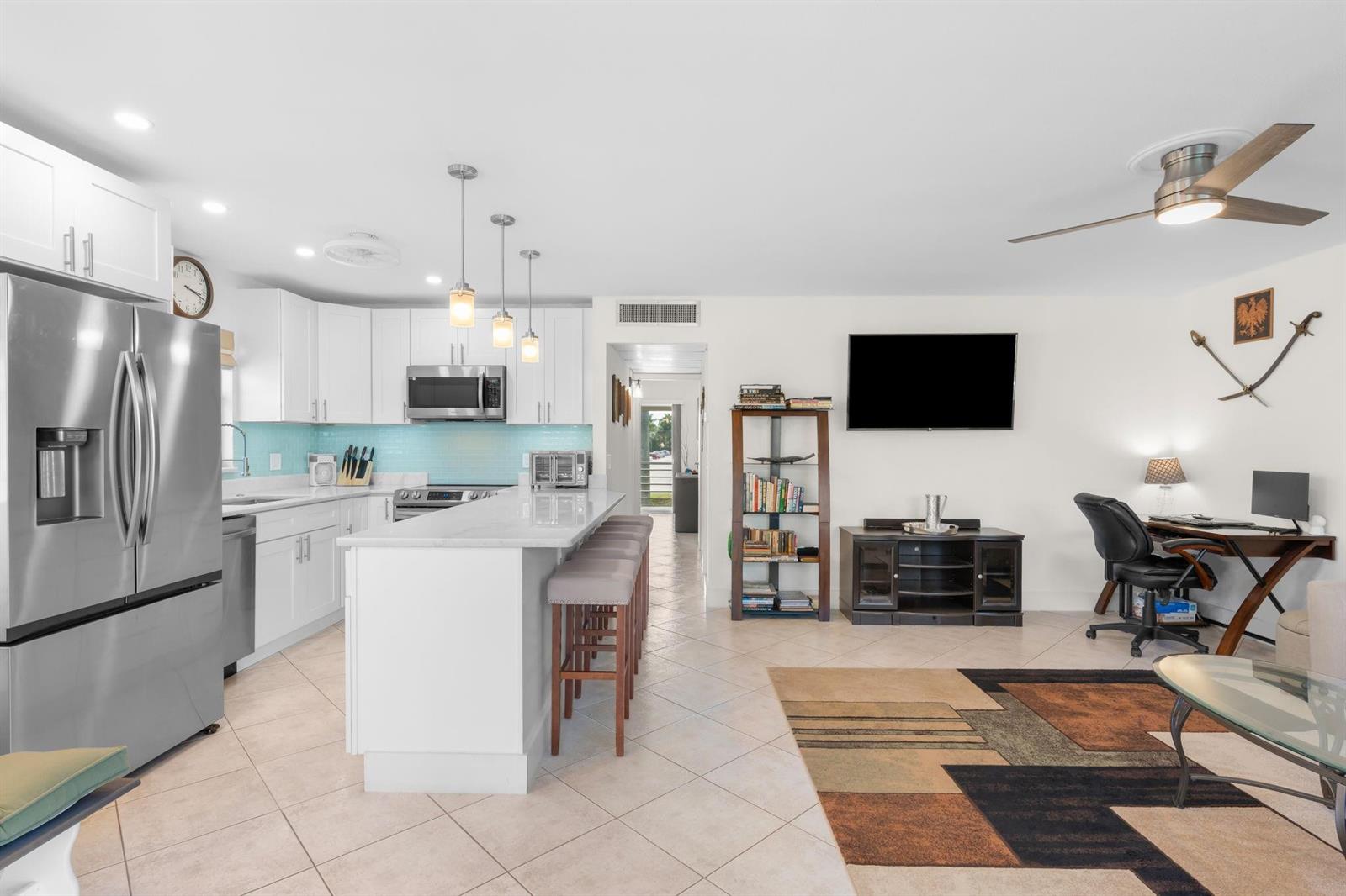 An open-concept kitchen and living area features white cabinetry, a marble island, and tile flooring — 189 Brittany D # 189, Delray Beach FL 33446, DELRAY BEACH, FL