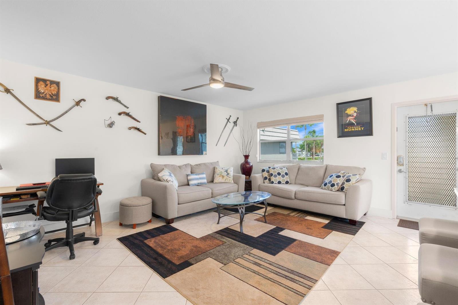 A living room features two beige sofas, a geometric area rug, and wall-mounted swords — 189 Brittany D # 189, Delray Beach FL 33446, DELRAY BEACH, FL