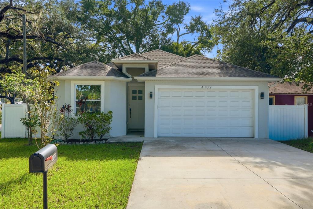 A single-story house with a white exterior, a two-car garage, and a concrete driveway — 4102 N 29TH STREET, TAMPA, FL