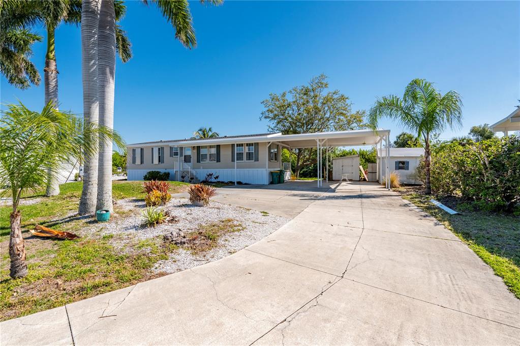 A single-story manufactured home with a concrete driveway, carport, and palm trees in the yard — 3004 BAMBOO COURT, PUNTA GORDA, FL