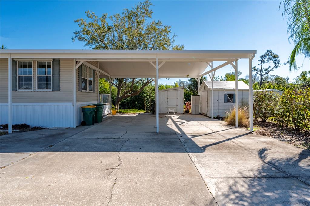 A concrete driveway features a covered carport attached to the side of a mobile home — 3004 BAMBOO COURT, PUNTA GORDA, FL