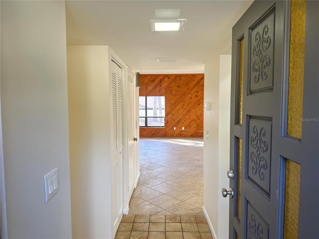An entryway leads into a living area with diagonal wood-paneled walls and tiled floors — 3808 NE 17TH STREET CIRCLE, OCALA, FL