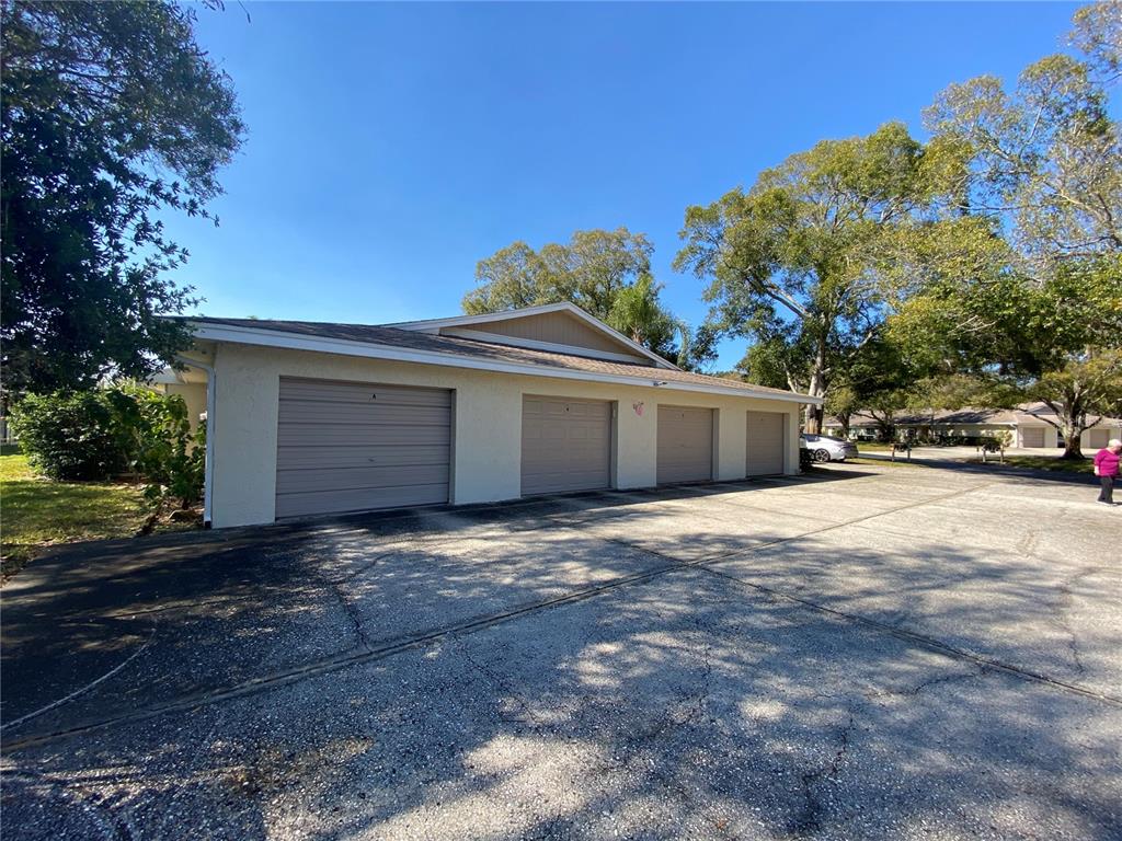 A row of four garage doors on a light-colored building with a concrete driveway — 1059 DUNROBIN DRIVE UNIT B, PALM HARBOR, FL