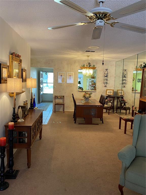 A dining area with a wooden table, ceiling fan, and mirrored wall in a carpeted room — 1059 DUNROBIN DRIVE UNIT B, PALM HARBOR, FL