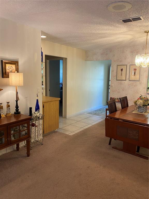 A dining room features carpeted flooring, a wooden table, and a sideboard with a lamp — 1059 DUNROBIN DRIVE UNIT B, PALM HARBOR, FL