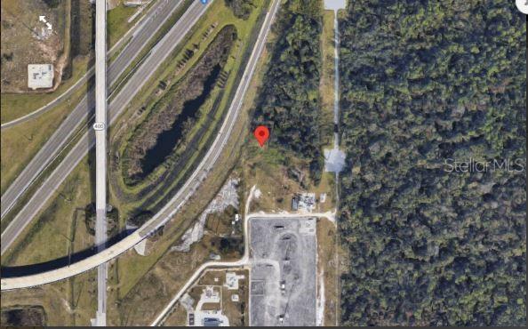 An aerial map view shows a red location pin on a wooded lot near a highway — N OLD LAKE WILSON ROAD, KISSIMMEE, FL