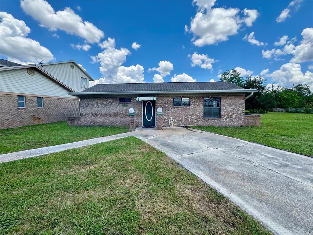A single-story brick house features a concrete driveway, a front walkway, and a dark door — 14371 US HIGHWAY 301 S, STARKE, FL