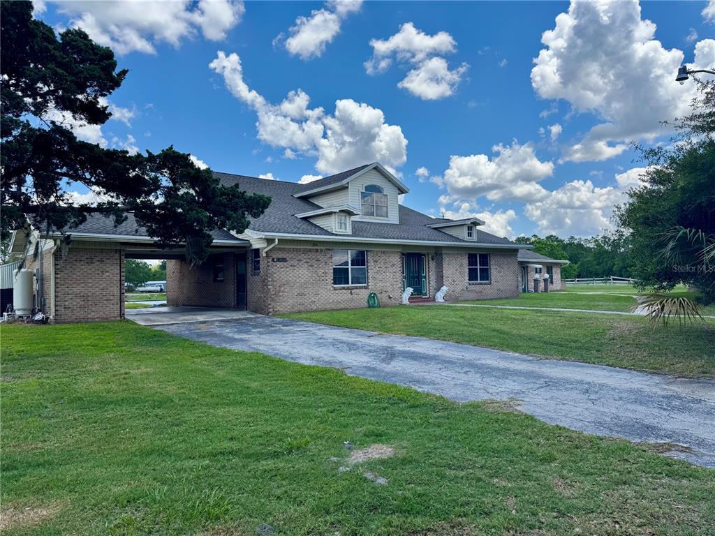 A brick house with a carport, a paved driveway, and a large grassy yard — 14371 US HIGHWAY 301 S, STARKE, FL