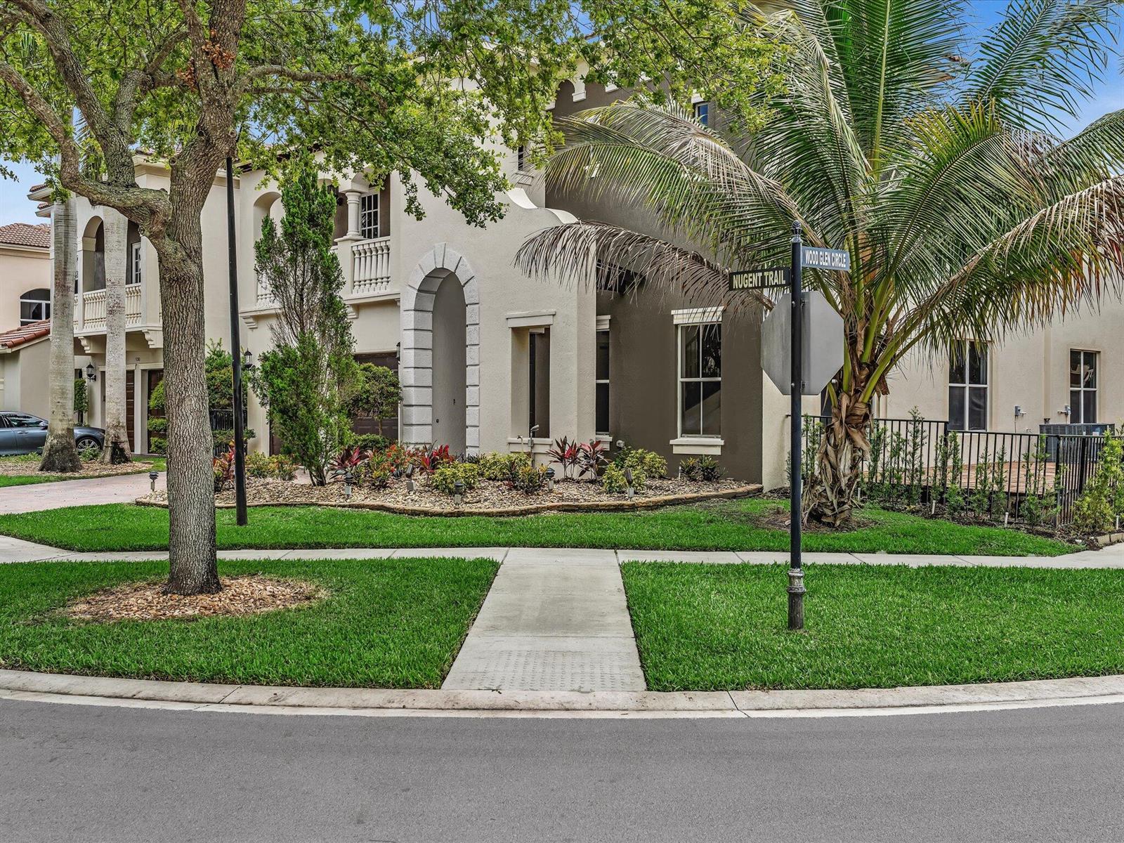 A two-story stucco house with an arched entryway stands behind a lawn and sidewalk — 9286 Nugent Trail, West Palm Beach FL 33411, WEST PALM BEACH, FL