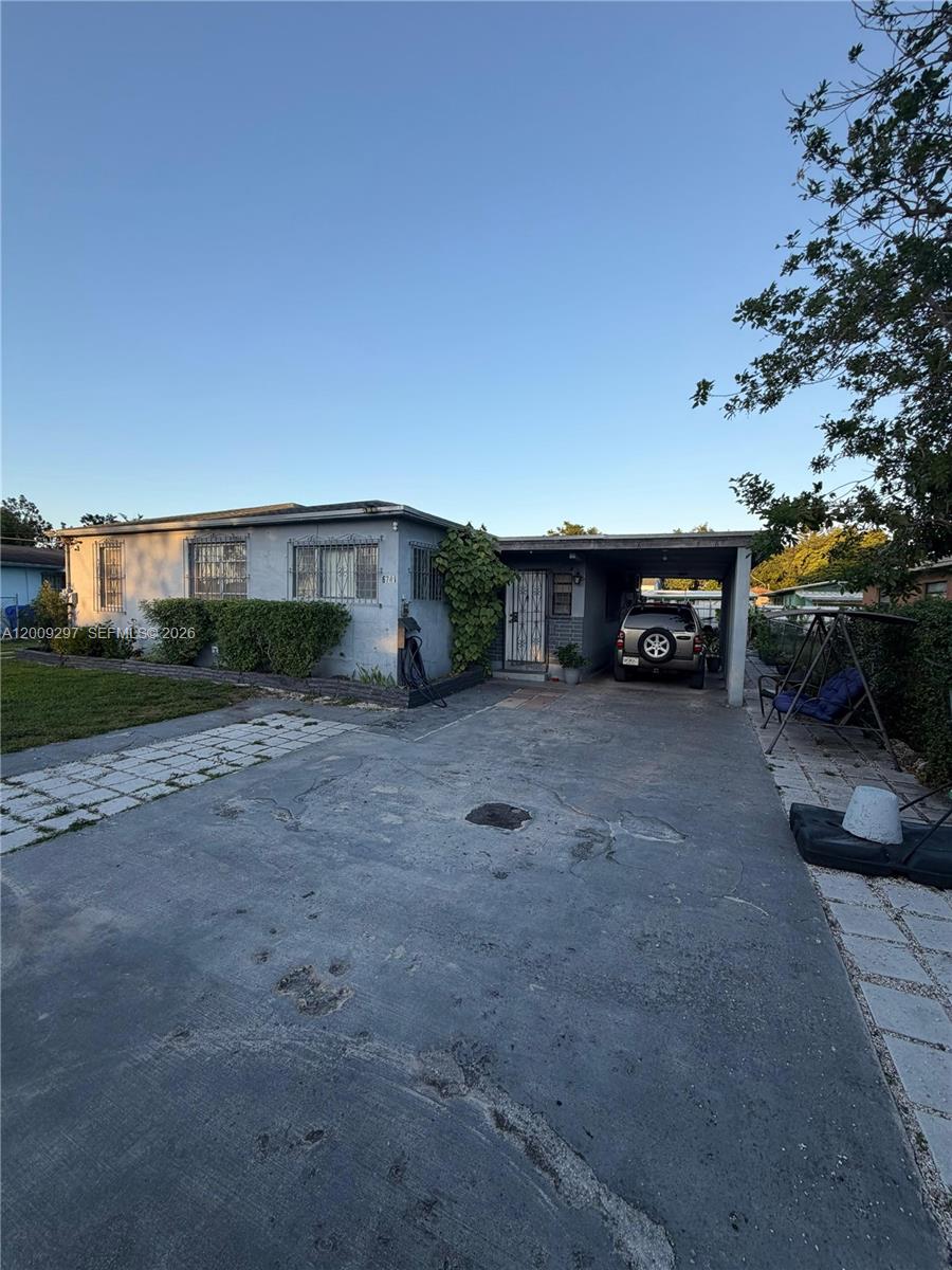 A single-story house with a concrete driveway, a carport, and security bars on the windows — 6741 NW 6th Ct, Miami FL 33150, MIAMI, FL