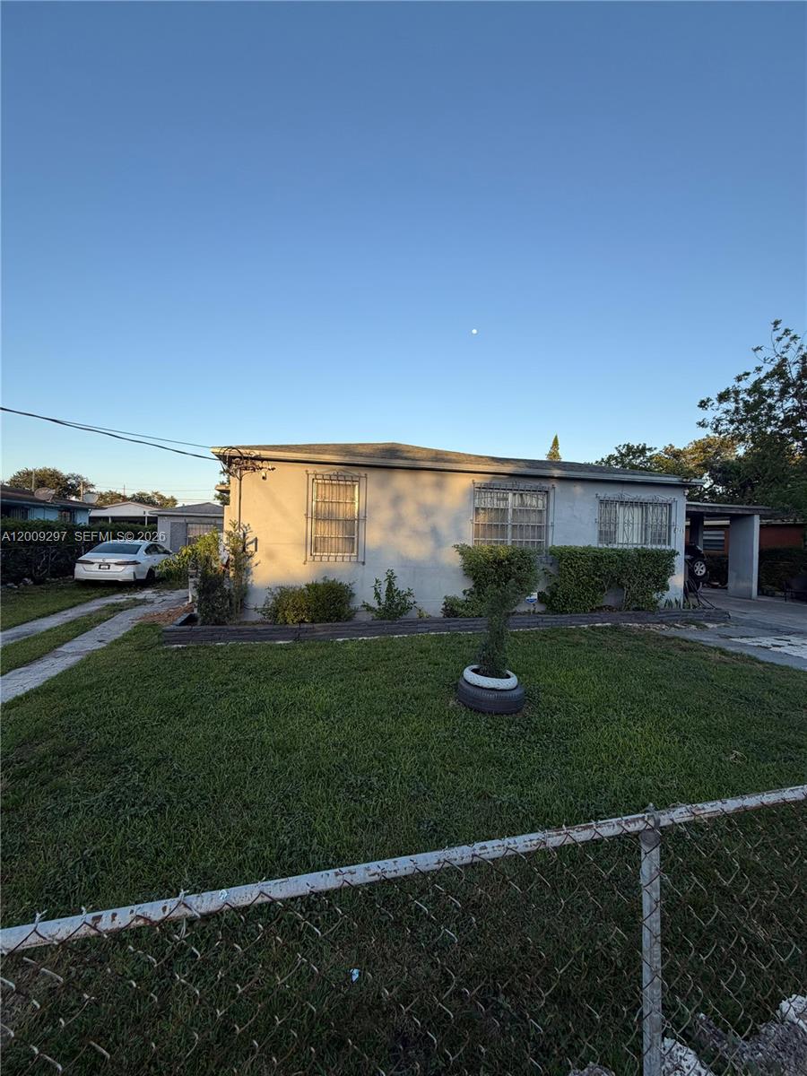 A single-story house with a lawn, chain-link fence, and a driveway with a parked car — 6741 NW 6th Ct, Miami FL 33150, MIAMI, FL