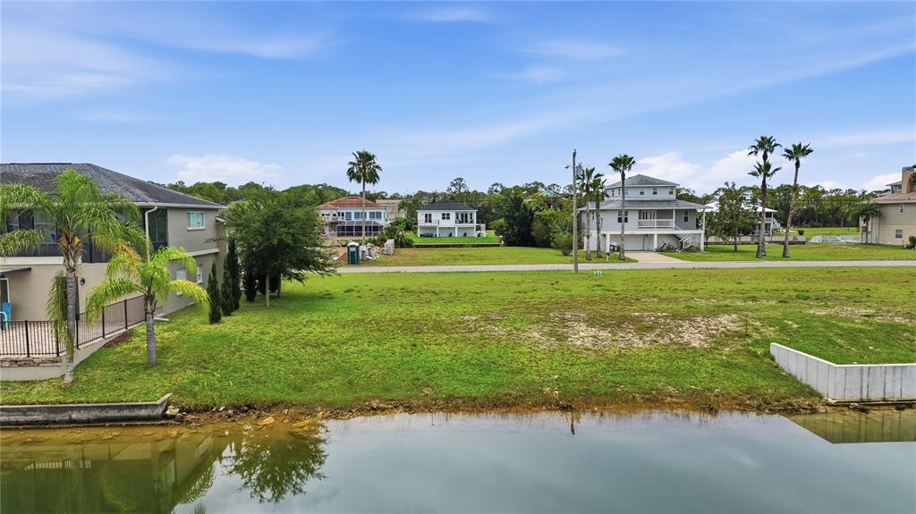 An elevated view shows a grassy waterfront lot with a neighboring house and canal — 3431 JEWFISH DRIVE, HERNANDO BEACH, FL