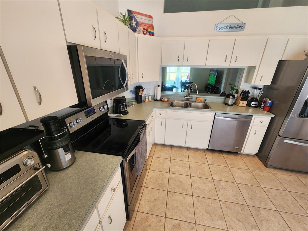 A kitchen with white cabinets, stainless steel appliances, and light-colored tile flooring — 2601 SUNDANCE CIRCLE, MULBERRY, FL