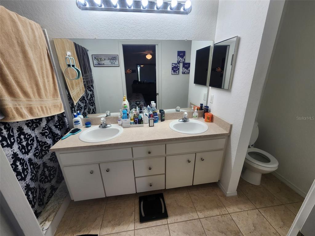 A bathroom features a double vanity with white cabinets, a large mirror, and a toilet — 2601 SUNDANCE CIRCLE, MULBERRY, FL
